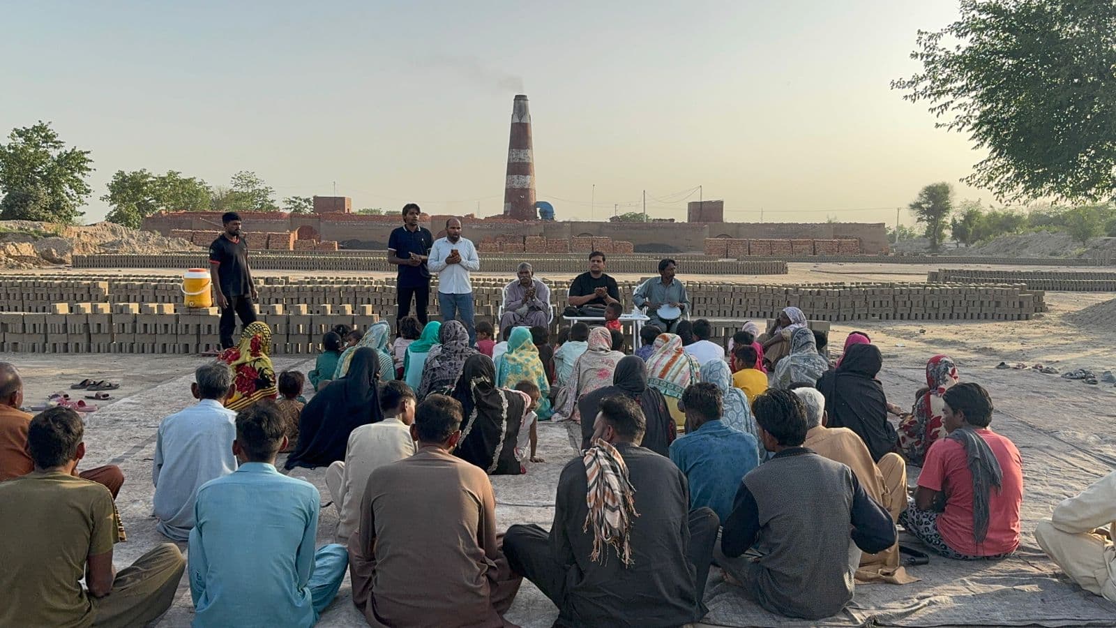 A worship gathering with families near a brick kiln